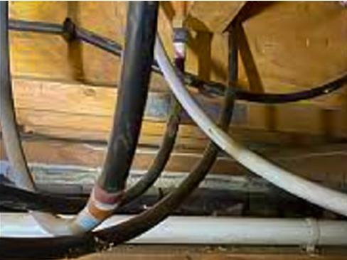 Black and grey polybutylene water pipes installed under an Auckland home in the 1970s, showing visible age